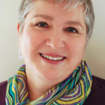 Picture of the Author Ellen Rumsey. She is smiling and wearing a colorful scarf. 